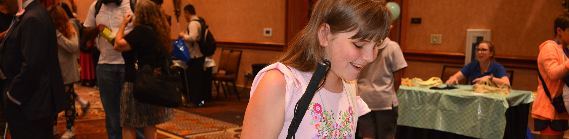 A young blind girl smiles widely at an NFB student event.
